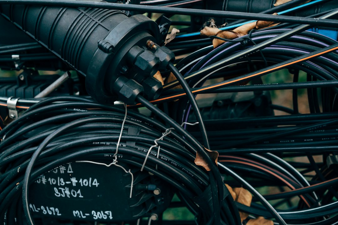 Bobinas de cabos de fibra pretos e uma caixa de emenda com etiquetas escritas à mão.